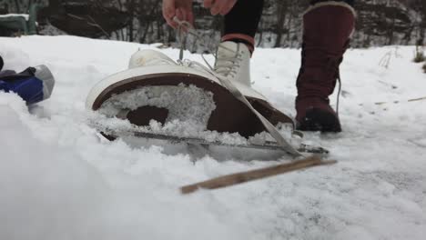 Mujeres-Desatando-Una-Bota-De-Patinaje-Sobre-Hielo-En-Un-Lago-Congelado