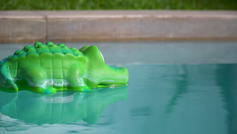 Alligator-chlorine-dispenser-floating-on-rippled-water-in-a-swimming-pool