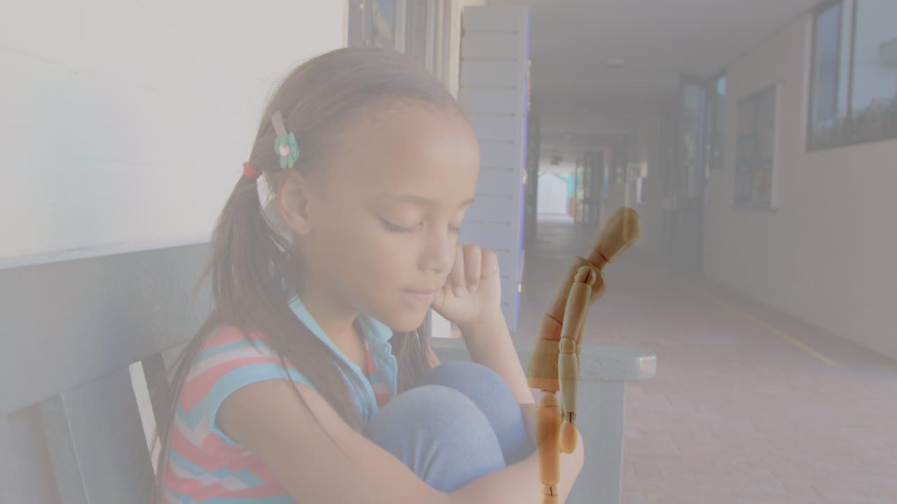 Video composito di una figurina di legno su sfondo di una ragazza afroamericana stressata in un corridoio di scuola