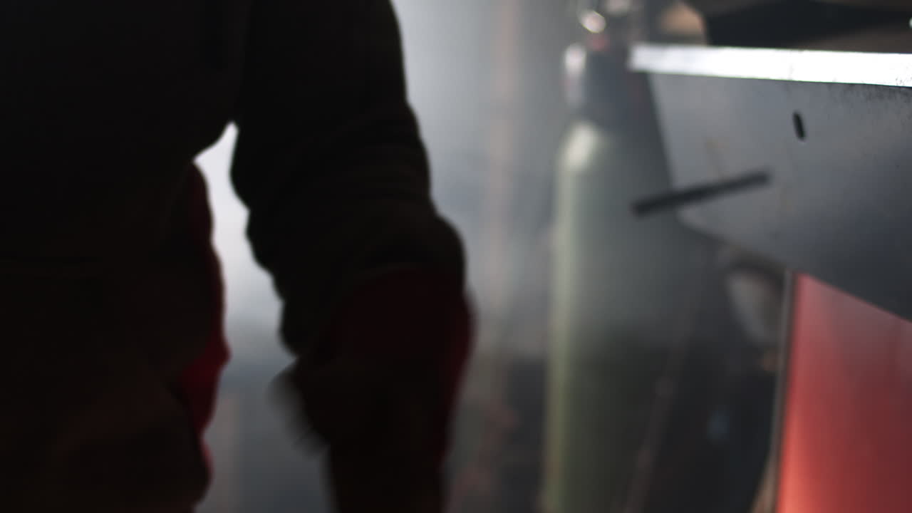 un herrero se pone guantes encima de una máquina de soldar en un taller