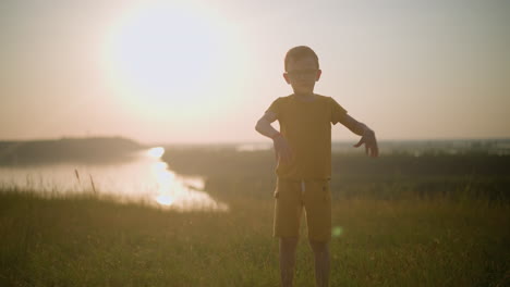 a young boy, dressed in yellow and wearing glasses, is captured mid-flip in a grassy field during a beautiful sunset. the warm, golden light enhances the vibrant energy of the scene