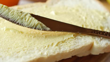 primer plano de la mantequilla que se está esparciendo sobre el pan
