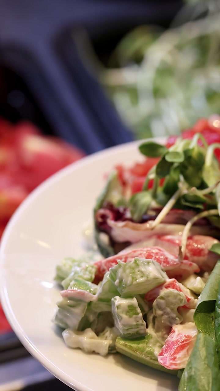 Primo piano rotante di un piatto di insalata mista fresca in un luminoso buffet self-service