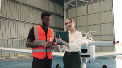 two people discussing airplane maintenance in a hangar
