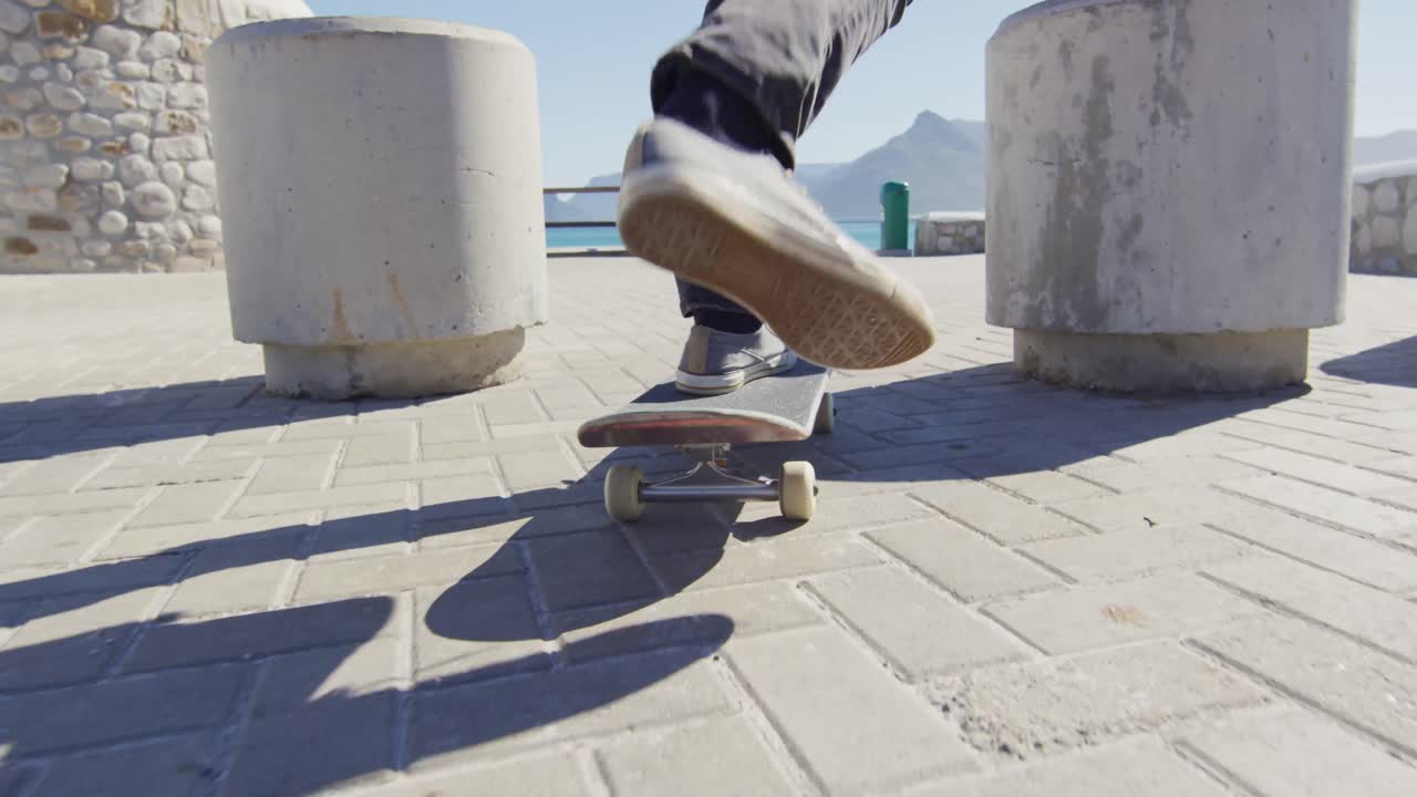 video de una sección baja de una persona patinando en un soleado paseo marítimo por la playa