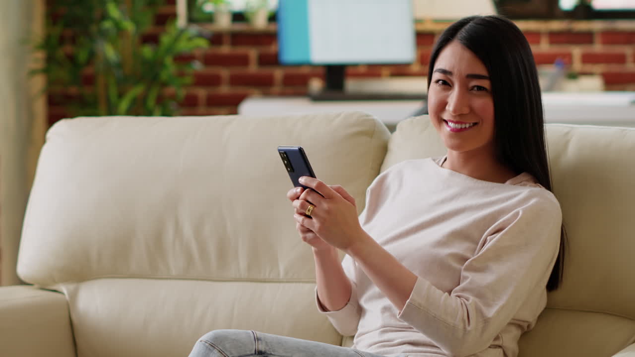 Woman sitting on couch using smartphone