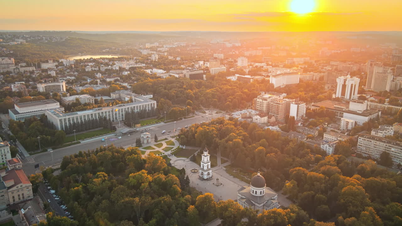 Aerial drone view of Chisinau downtown at sunset. Panorama view of multiple buildings, central park, roads with moving cars. Moldova
