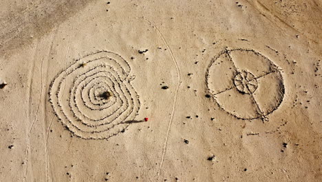 Woman-in-Red-Dress-Runs-Around-Strange-Circles-in-Sandy-Desert,-Drone-Top-Down