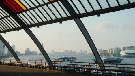 Paisaje-Urbano-De-Amsterdam:-Vista-Matutina-Del-Río-Amstel-Con-Ferry,-Visto-Desde-La-Plataforma-Del-Autobús-De-La-Estación-Central,-Gaviotas-En-El-Cielo