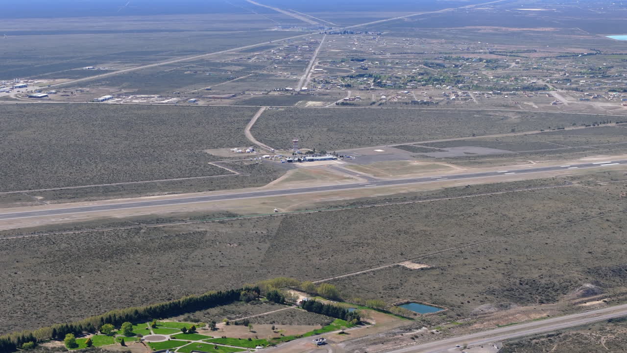 Aerial view of El Tehuelche Airport, located near Puerto Madryn, province of Chubut, Argentina, showing the runway, terminal building, and surrounding landscape, drone slow motion establishing shot