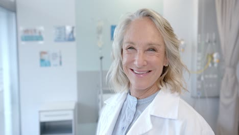 Portrait-of-happy-senior-caucasian-female-doctor-in-hospital-room,-slow-motion