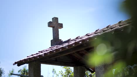 christian cross on top of exterior building with green trees in the wind on a sunny day