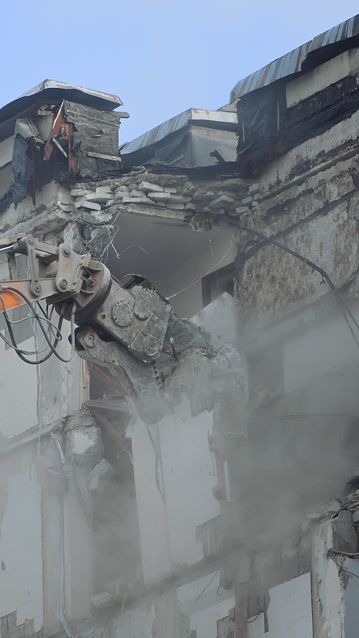Demolizione di un vecchio edificio residenziale. Distruzione di una vecchia casa con un escavatore a benna in cantiere.