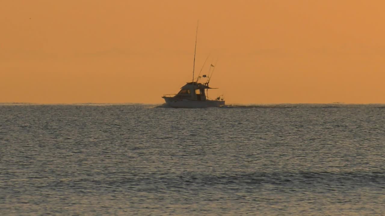 Motoscafo che naviga all'orizzonte su un mare calmo e argenteo all'alba, al rallentatore.