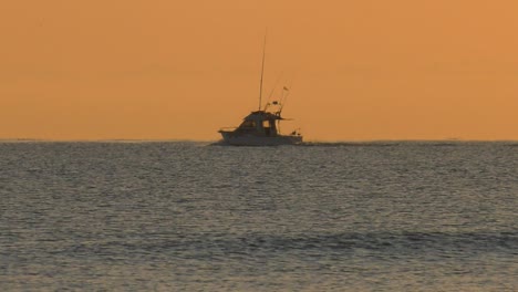 motor boat sailing on horizon on calm silver sea at dawn, slow motion