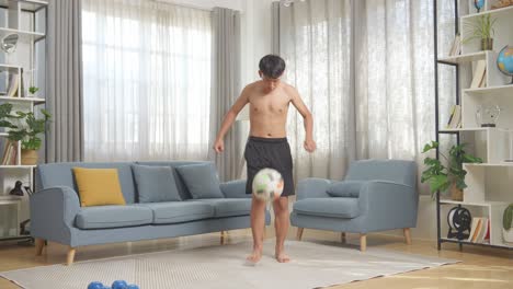 cuerpo lleno de niño adolescente asiático haciendo habilidades de fútbol durante el entrenamiento sin camisa en casa