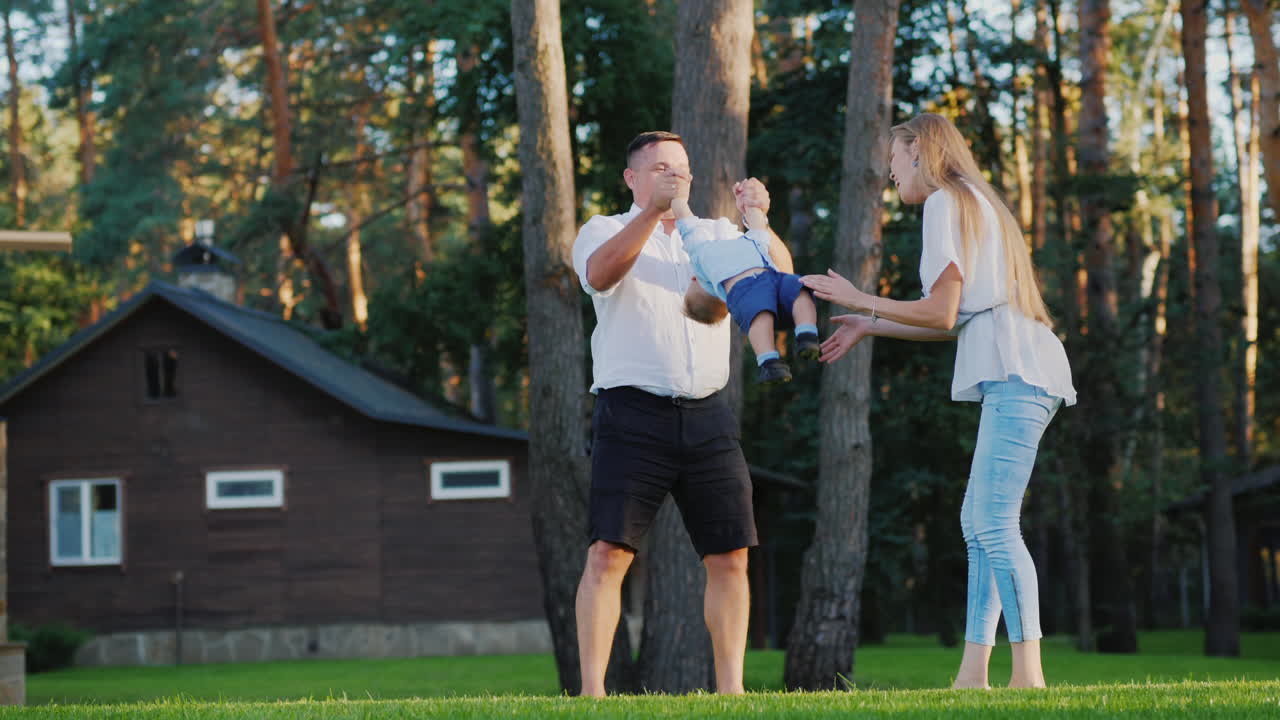 familia joven feliz jugando con su hijo de 1 año en el video en cámara lenta del patio