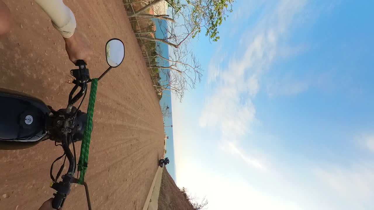 Left Hand Adjusting Bike Mirrors While Driving On A Gravel Road Next To A Beautiful Seaside Village In Phan Thiet, Vietnam. Motorbiking POV, Vertical Shot.