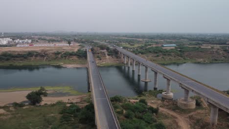 Highway-bridge-built-over-the-river-basin-in-the-rural-terrain,-India,-Aerial-view,-Slow-motion