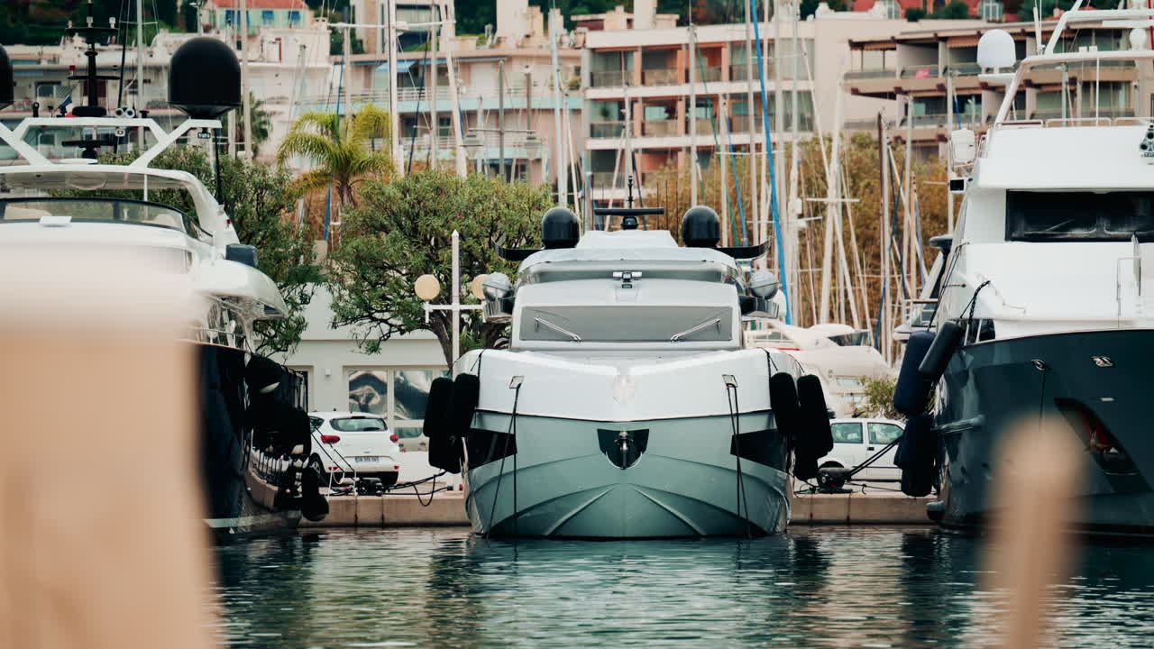 A modern white yacht docked in a marina, viewed from the front