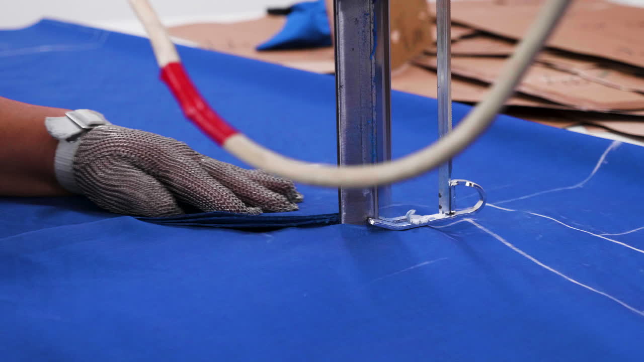Female worker in a fabric factory using a disc knife to cut cloth