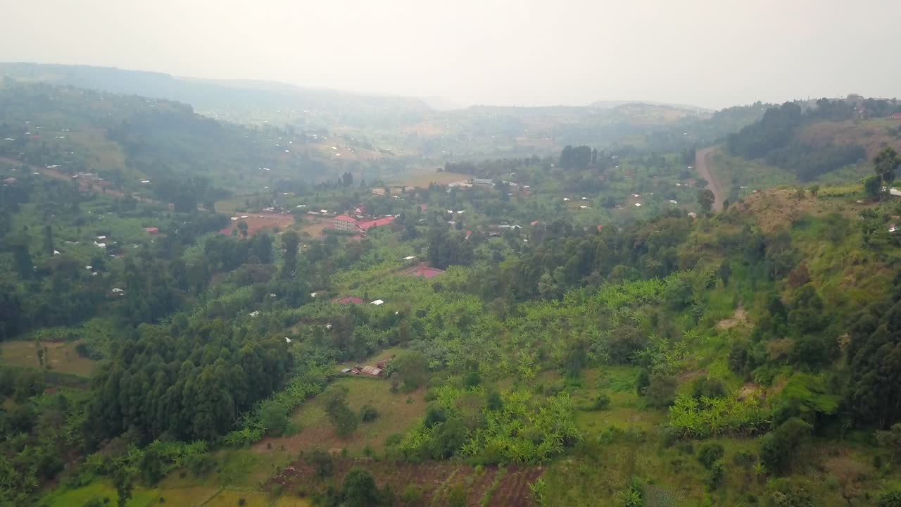 Drone captures green farmlands and dense vegetation in Kapchorwa, Eastern Uganda, on the slopes of Mount Elgon during overcast dry season, revealing rural settlement and patchwork of cultivated land