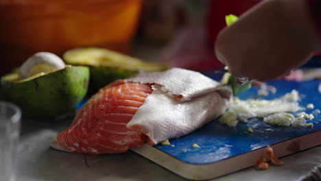 sushi ingredients including fish and avocado arranged on counter in preparation scene, chef peels and trims thin slices of ginger