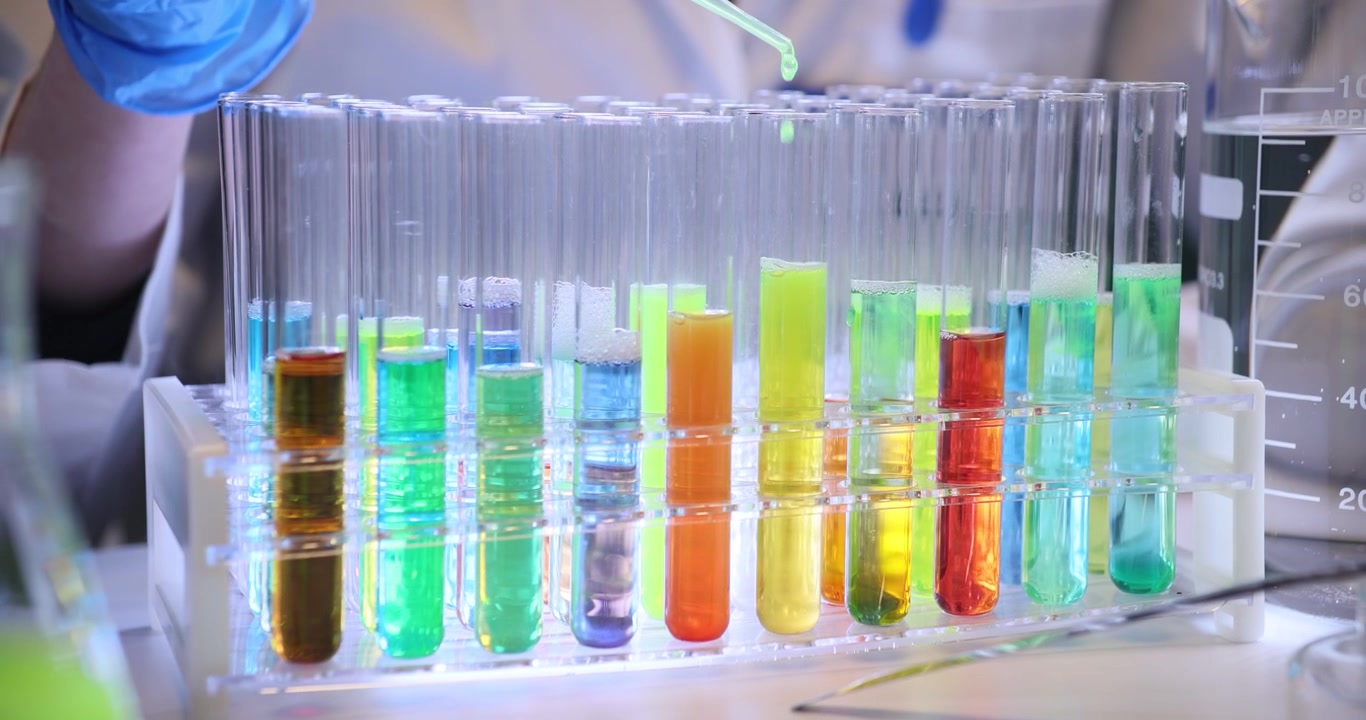 Scientist hand drips reagent into test tubes with color fluids