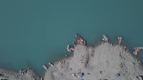 Vista-Aérea-De-Pájaro-De-Los-Barcos-Amarrados-En-La-Orilla-Del-Lago-Attabad