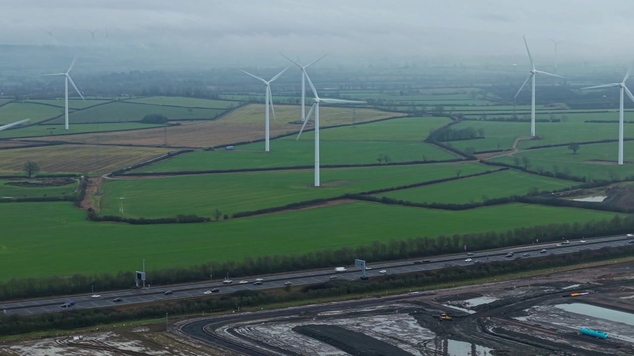 Drone view of renewable energy wind farm and busy highway transport link near Yelvertoft.