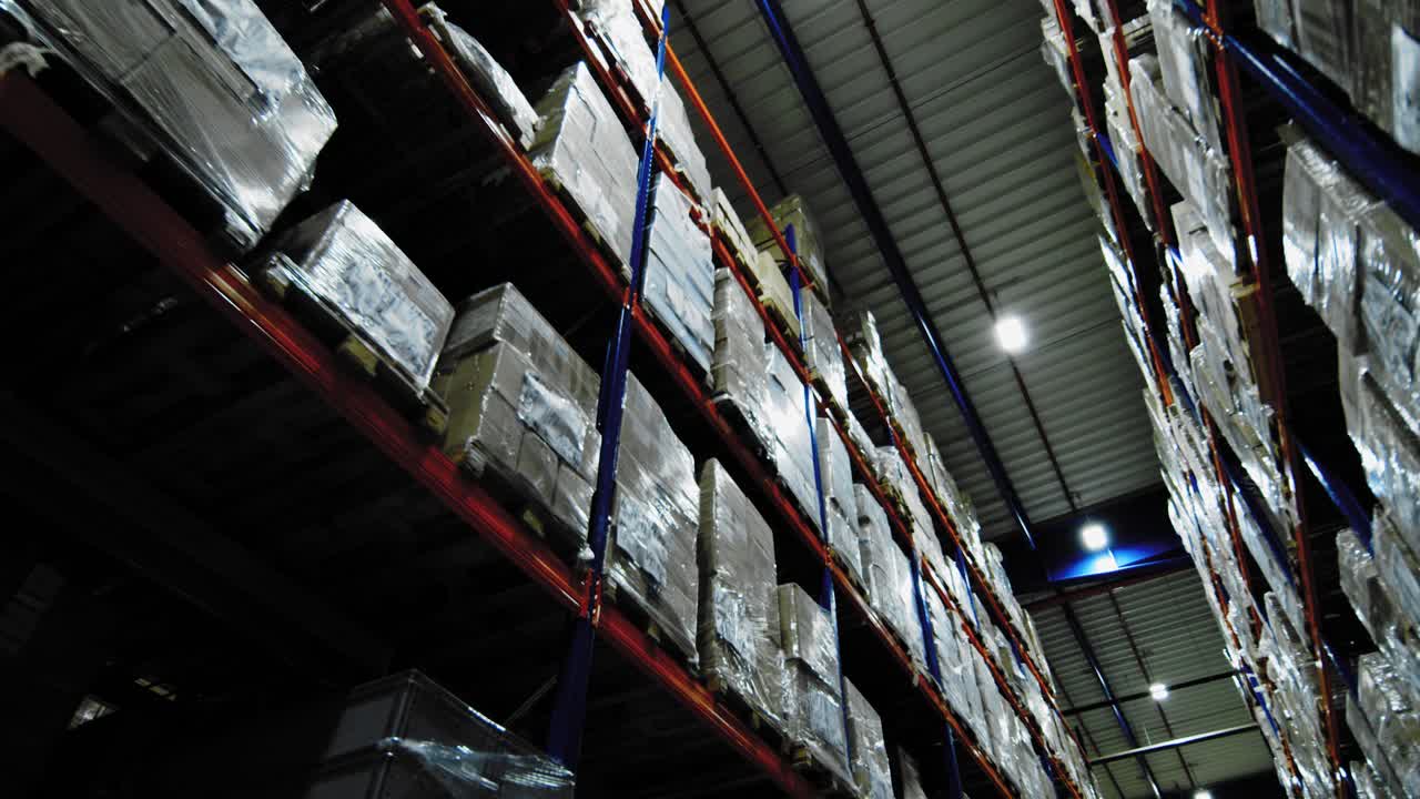 Packages stacked high on shelving system of industrial warehouse; storage facility