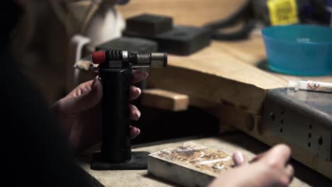 Shot-of-a-female-metalworking-jeweller-turning-on-a-small-blow-torch