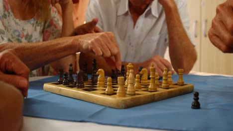 Mid-section-of-senior-friends-playing-chess