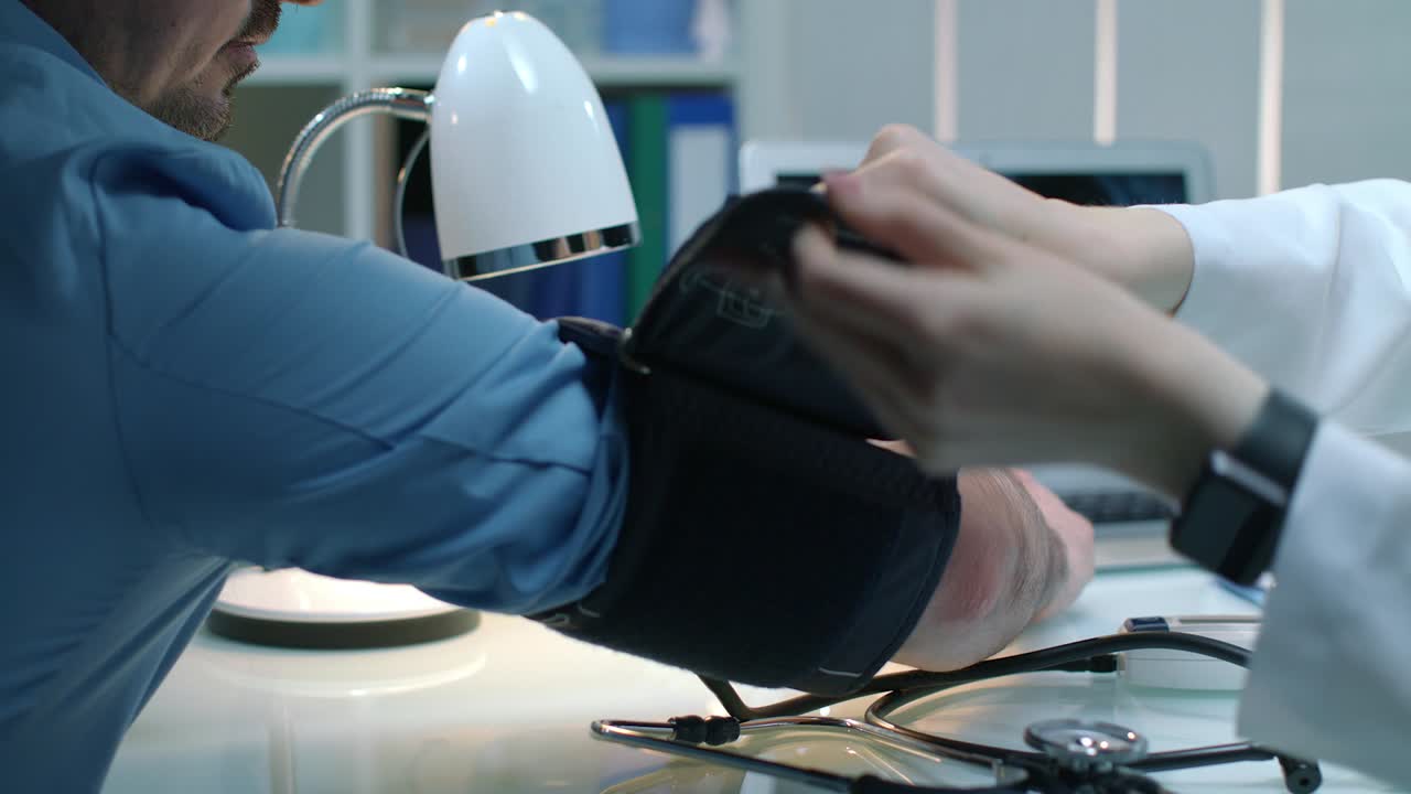 여성 의사가 압력을 측정하는 남성 환자. 남성은 저혈압을 확인합니다.