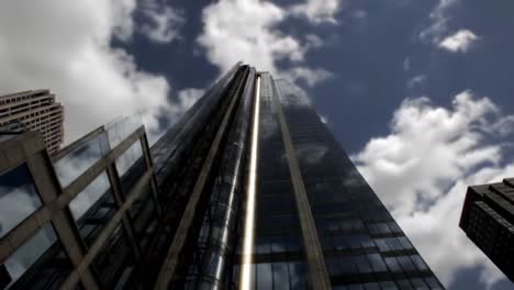 a dramatic perspective of a skyscraper against a cloudy sky capturing the play of light and shadows amidst modern urban architecture