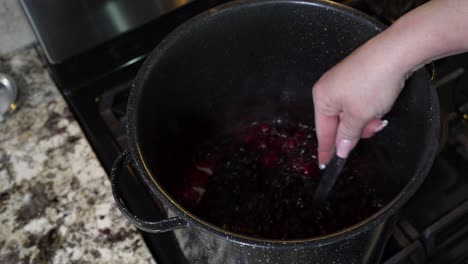 Stirring-the-sugar-into-a-pot-full-of-raspberries-and-blueberries-to-make-jam---slow-motion