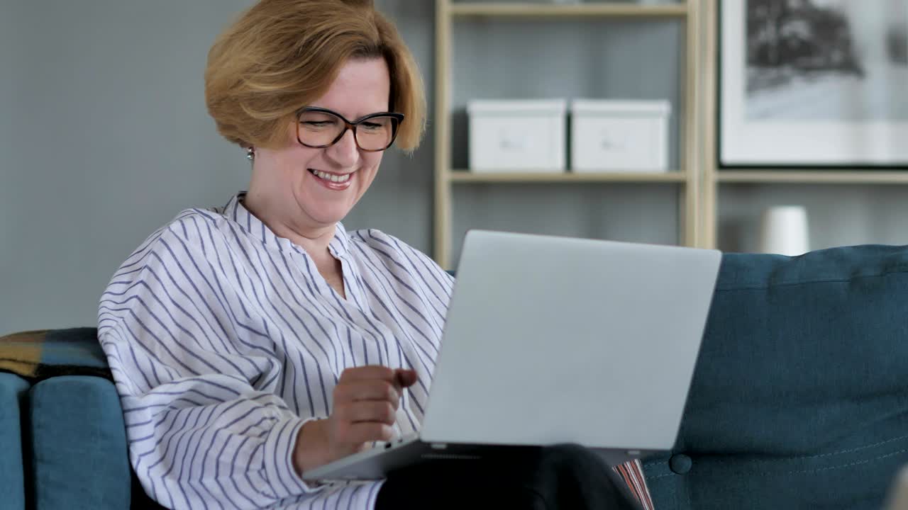 anciana excitada celebrando el éxito, trabajando en una computadora portátil