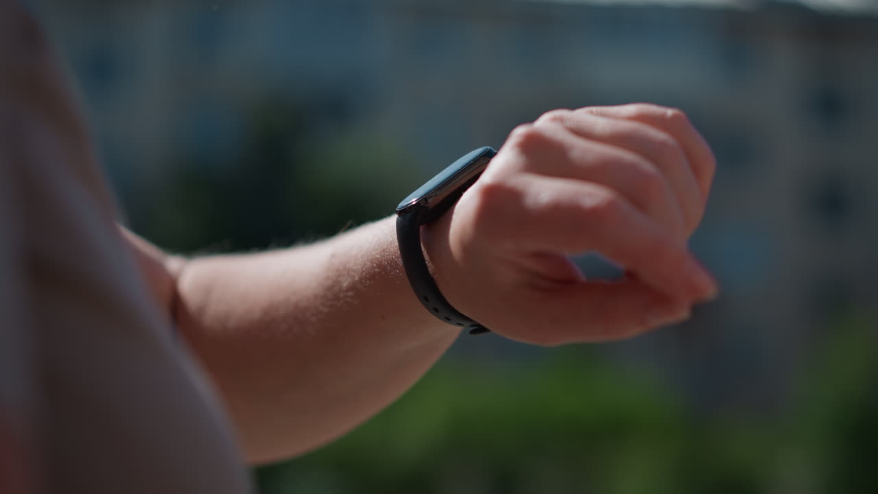 Close up of lady checking time on smartwatch under sunlight, blurred building background adding urban depth, moment capturing modern lifestyle, punctuality, and connection between technology