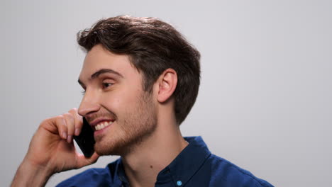 Positive-man-talking-on-smartphone-on-light-background.-Guy-calling-on-cellphone