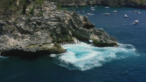 large ocean waves creating a natural whirlpool in crystal bay nusa penida bali during a sunny day, aerial