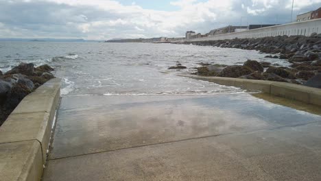 grada de barco desde el paseo marítimo hasta el agua con olas rompiendo
