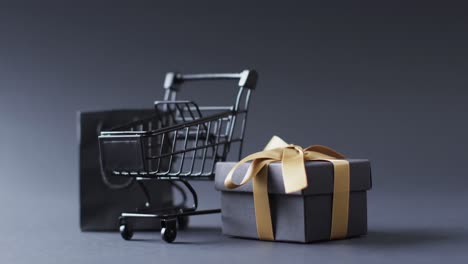 video of shopping trolley, shopping bag and gift box with copy space over grey background