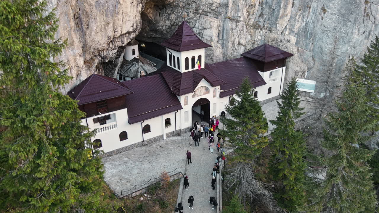 Aerial drone view of The Ialomitei Cave in Romania. Entrance into the cave with tourists in Bucegi Mountains