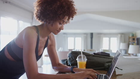 young woman downloading data from personal health tracker to laptop after exercise