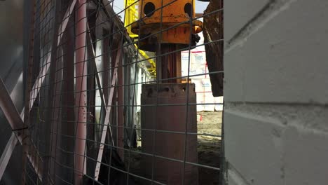 wide shot of drill bit pipe from a hydraulic rotary drilling rig being lowered into place, then rotation of drill column