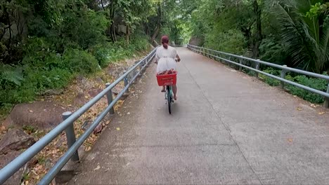Mujer-En-Bicicleta-Blanca-Navegando-Por-La-Carretera-A-Través-De-La-Jungla-En-La-Isla-De-La-Digue,-Seychelles