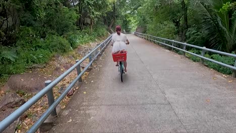 woman in white coasting bicycle down road through the jungle on la digue island the seychelles