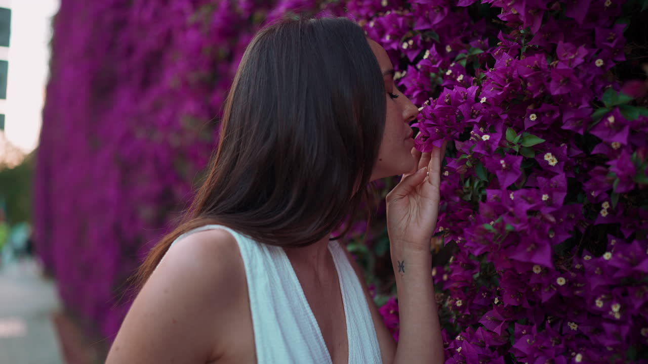 Donna che ammira fiori viola di buganvillee