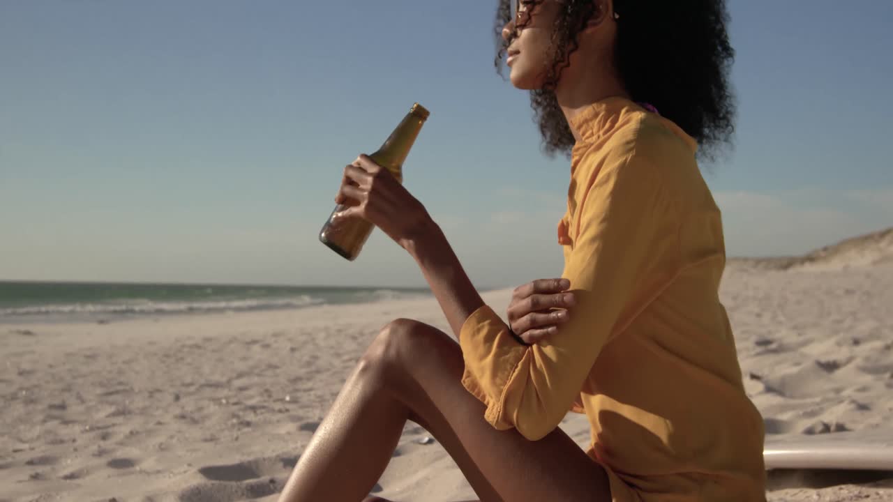 Donna che beve birra in spiaggia 4K