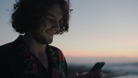 joven usando el teléfono enviando mensajes de texto por la playa esperando el atardecer el amanecer